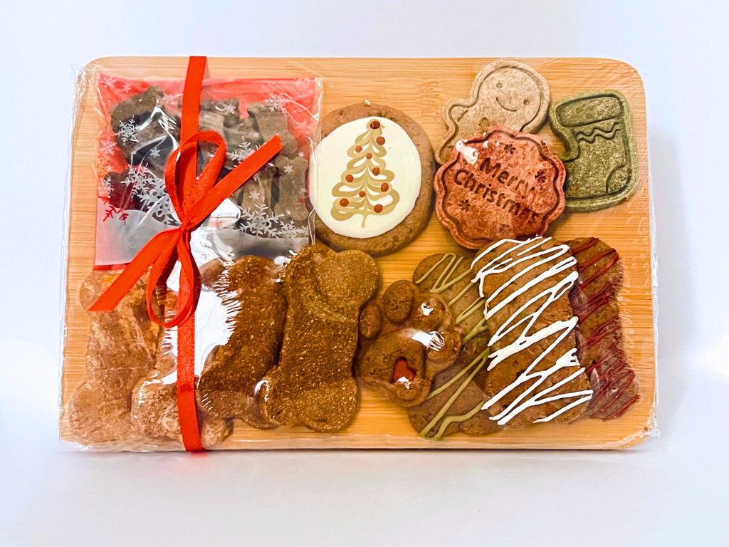 Assorted dog treats on a wooden board with a red ribbon