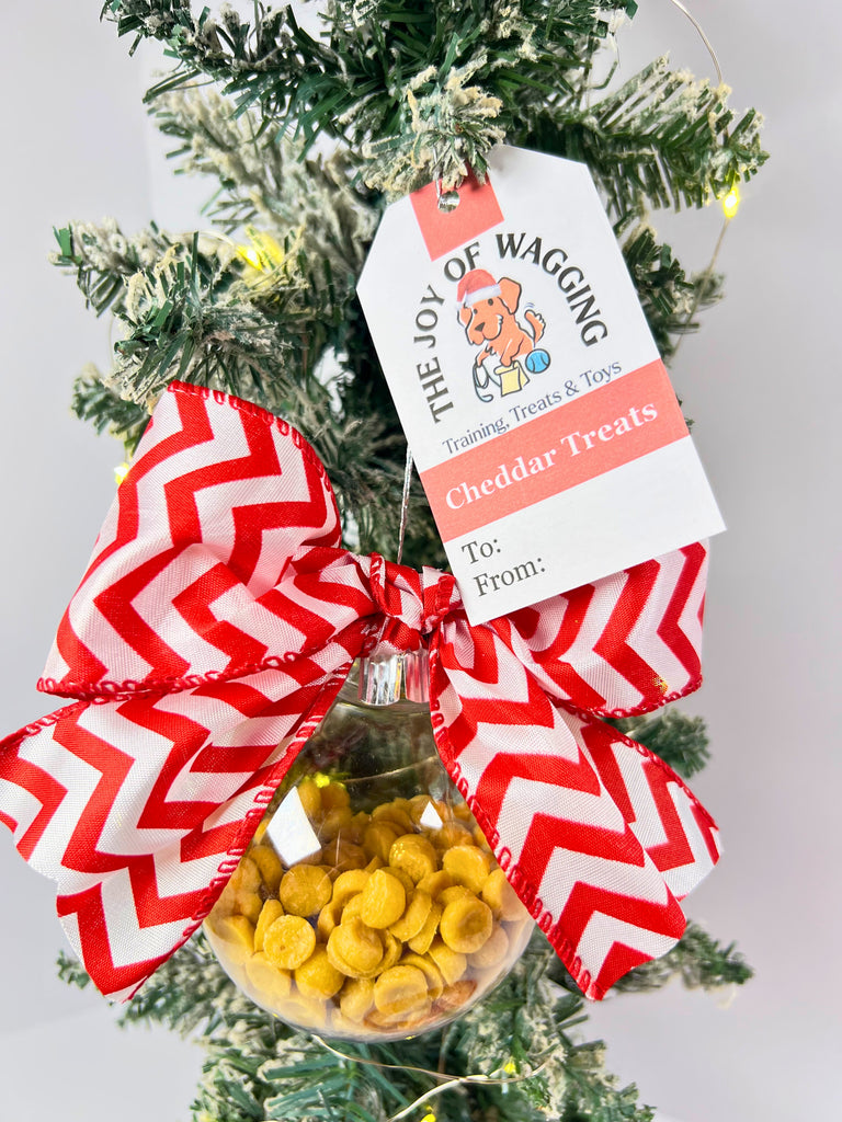 Decorative Christmas ornament with cheddar dog treats and a red and white bow with a gift tag.